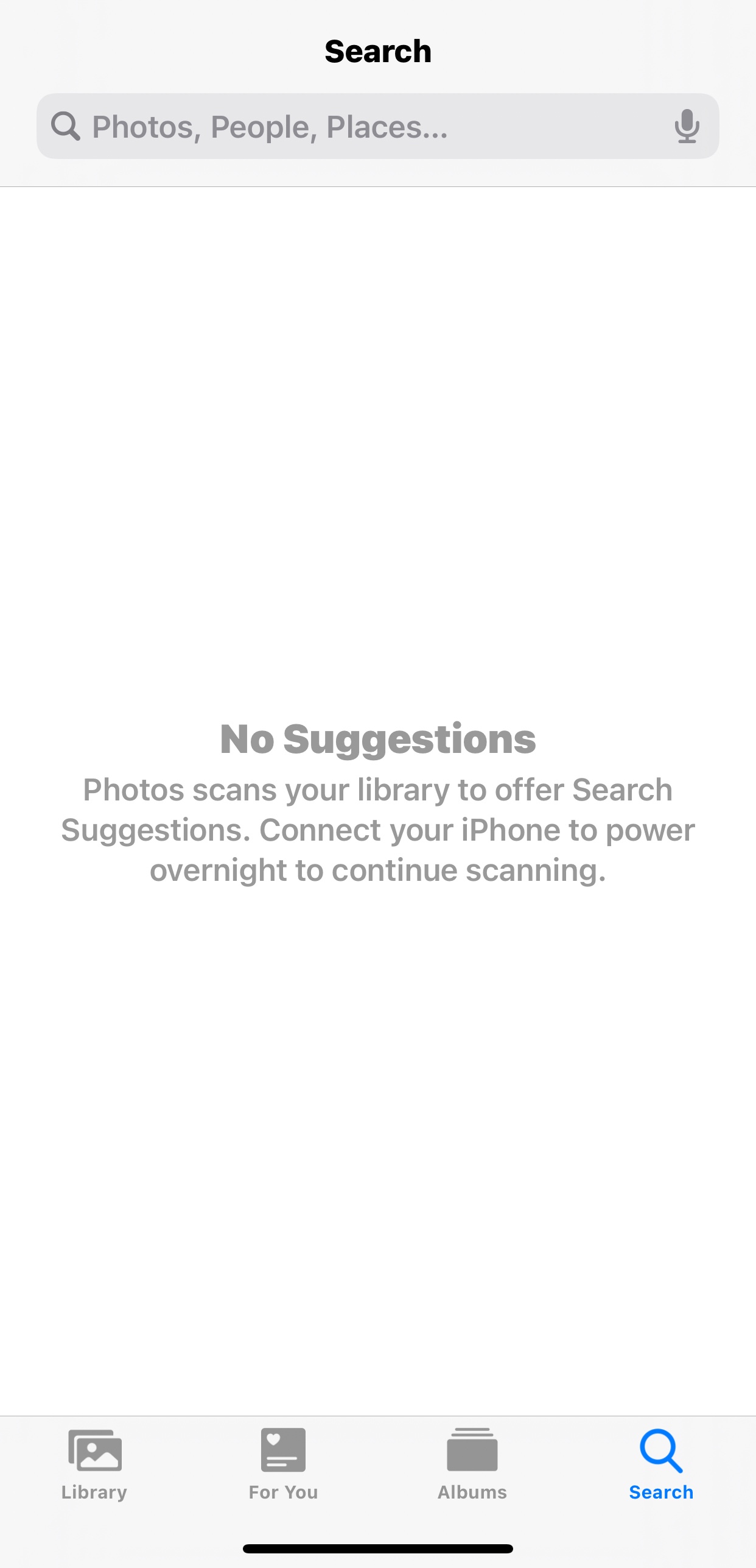 iPhone photos app screenshot showing message "No Suggestions. Photos scans your library to offer Search Suggestions. Connect your iPhone to power overnight to continue scanning"